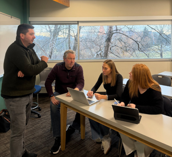 A woman with blond hair hands a Christmas stocking to a woman with long brown hair